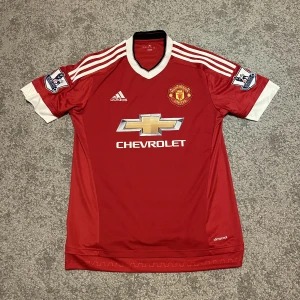 Manchester United Fotbollströja - Manchester United fotbollströja 2015-2016 med PL patches. Tröjan är i gott skick och med det ser den bra ut. Säljer pga att jag inte har någon användning av den plus att den är för stor för mig. Pris kan diskuteras.