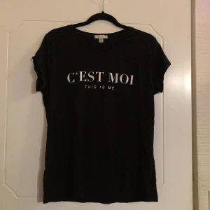 Svart T-shirt med tryck - svart t-shirt med texten ”c’est moi” på bröstet. köpt på h&m för några år sedan och är flitigt använd men i bra skick. storlek XL men känns mer som M-L. skicka pm om du har frågor eller vill se fler bilder <3 