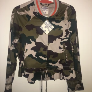 Baum und Pferdgarten tunn jacka - En tunn jacka från Baum und Pferdgarten storlek i storlek 36. Kamouflage/militär mönstrad. Den har snörning vid midjan, blir lite peplum när man knyter den. Aldrig använd, ny med prislapp kvar. Säljer för 900kr inkl frakt, nypriss 1999kr