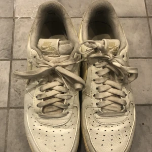 Nike skor - Ett par vita Nike skor med gul sula och gul Nike symbol, dem är i bra skick och har nästan inga skador. Skosnörena är lite smutsiga men finns att köpa billigt