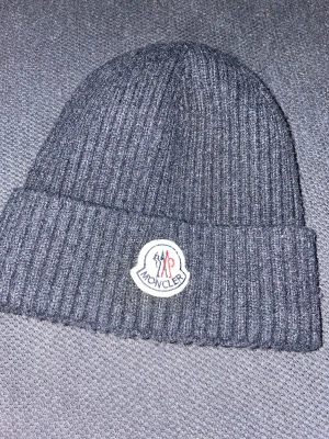 Moncler mössa  - Moncler mössa i grå/mörk blå färg. 