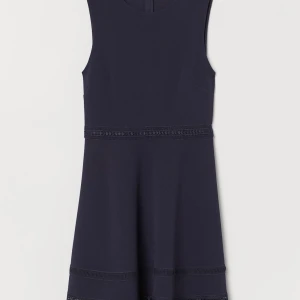 Klänning med spetsband - En kort, ärmlös klänning i stadig trikå med struktur. Klänningen är avskuren med spetsband i midjan och har utställd kjol med spetsband nedtill. Dold dragkedja bak.  Komposition - Spets: Polyester 100%, Elastan 5%,