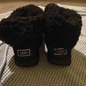 UGGs svarta - Ett par svarta uggs, med kristall detalj och mysigt foder, dem är slitna, men har inga hål eller skador, skorna är i storlek 38 och passar perfekt till höst/vinter. Använder inte längre då de blivit för små. Original pris 2000 kr 
