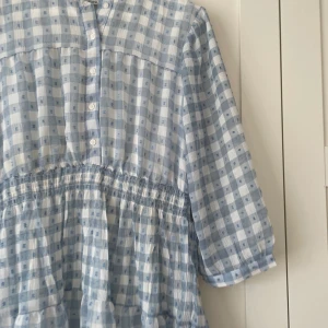 Blå rutig mini klänning  - Blå rutig klänning med knäppning. Köpte för 2 år sedan men bara använd 2 gånger. Knälång. 