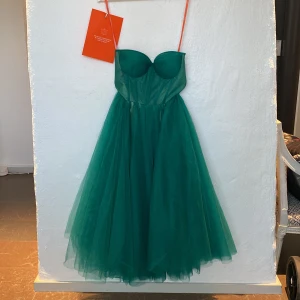 Balklänning - Milla balklänning i tyll. Axelbandslös med korsett över bysten. Aldrig använd. Storlek M