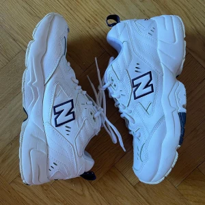 NEW BALANCE 608 - Sparsamt använda! Kritvita med mörkblå detaljer, nytvättade så känns helt sådär krispvita fortfarande utan några fläckar, märken el skavanker. I väldigt bra skick helt enkelt!