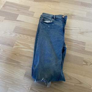 Ljusblåa jeans med slitningar i knäna storlek 44
