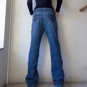 Jeans med rhinestones  - Jeans med rhinestones och mönster. Köpta på beyond retro och knappt använda då de är för stora för mig. Liten slitning längst ner.  Jag är 170 cm. Innerbenslängd: 79 cm Midjemått: 84 cm.