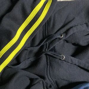Svart hoodie - En svart hoodie med gula ränder. Väldigt fin och mysig nu till kallare väder. Säljs då den inte används, annars inga defekter! 💗 både fraktar och möts upp i Stockholm. 🚚❤️ Tveka inte med att höra av dig. 