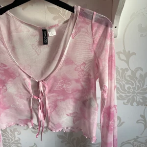 Kofta - Supersöt kofta i vitt och rosa med rosetter. Har aldrig kommit till användning, genomskinligt material. 🌸