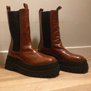 Nya bruna chelsea boots med platå - Krokodilmönstrade bruna chelsea boots med platå, nya och oanvända. Nypris 587kr, helt slutsålda. Frakt tillkommer eller så kan de hämtas i Sundbyberg :)