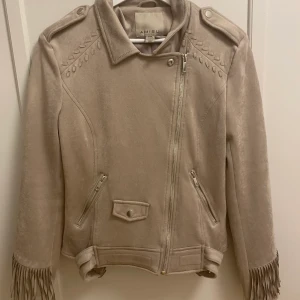 Amisu jacka med fransar - •En beige, lite ”cowboy” inspirerad jacka med fransar från Amisu •Storlek 38 •Använd ett fåtal gånger, mycket fint skick •Mitt pris 280 kr 