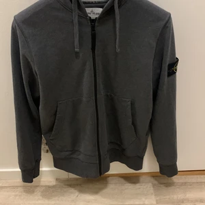 Stone island hoodie  - Stone island hoodie med mörkgrå färg i storlek L (små i storleken så passar en M också) köpt på NK i Stockholm för 3000, har två små hål på vänster bakaxel, har använt den ett fåtal gånger och förutom hålen så är den väldigt välskött. Kan pruta ner priset