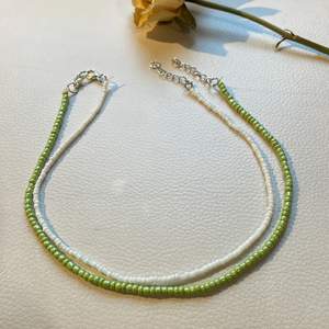 Två halsband, en av de gröna pärlorna, den andra av de mindre, vita pärlorna. De passar perfekt som delikata accessoarer 