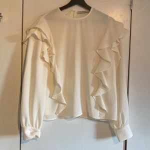 Vit blus - Vit blus med volanger. 100% polyester. Använd 1 gång. Storlek 40 men passar strl 38.