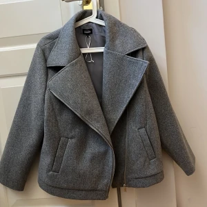 Trendig kappa - Nu säljer jag min korta kappa, skulle säga att den är använd 1 gång då den inte sitter som önskat på mig. Så nyskick, den gråa färgen tar sig inte riktigt på bilden, den är ljusare i verkligheten. Hör av er vid intresse eller frågor