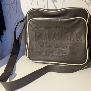 Väska - Perfekt skol väska, mycket utrymme. Använd men ändå i bra skick. Brun med vita detaljer. Oskänt märke.