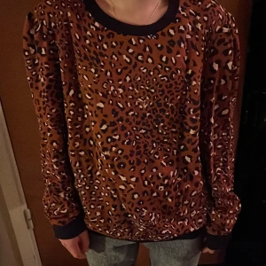 Baum und Pferdgarten  - Leomönstrad tröja i tunnare sweatshirttyg.brun botten och mörkblå muddar. Lite rynk på axeln. Sparsamt använd.