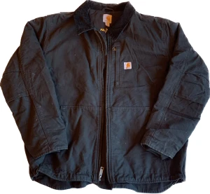 Carharrt Detroit Jacket - En svart carharrt jacka i riktigt bra skick. Den är hel svart och storlek XL/L. Mått; Bredd (67), Längd (72), armar(66). Kolla gärna in mina andra jackor!