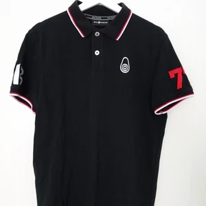 Pikétröja - Pikétröja från sail racing, sparsamt använd och fint skick. Svart med röda och vita detaljer. Ordinarie pris ca 800kr.