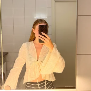 Topp - En beige tunn topp som är lite lätt genomskinlig, perfekt att ha en bralette under tex.  Kan användas som kofta men även att knyta ihop som på bilden.  Använd fåtal gånger.    