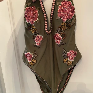 Grön baddräkt  - Grön baddräkt, sparsamt använd. Låg rygg med knytning i nacken. 