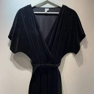 & Other stories lång jumpsuit - Svart, glittrig, fullång jumpsuit med djup urringning och knytning i midjan. Storlek S/165cm. Använd en gång. Köpt för 800kr