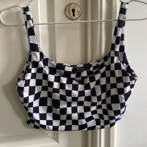 Schackrutigt linne - Säljer ett jätteskönt linne med schackrutigt mönster. Kan användas som ett kortare linne under en kofta eller kavaj. Men kan även användas som bikini topp.