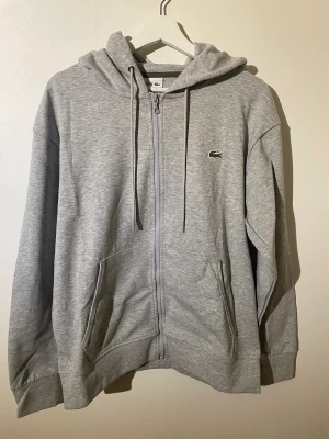 Lacoste zip-up - Zip-up hoodie från Lacoste i storlek M. Tröjan är i nyskick och inga tecken på användning finns.