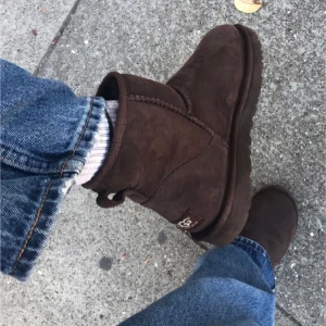 UGG Mini Darkbrown - Ugg Mini, mörkbruna i strl 36 Använd fåtal gånger, impregnerade. Inget utöver det vanliga vid användning att anmärka på förutom vecket fram till på skon. Mockan fortfarande borstad utseende, ej utsatt för vatten, insida inte nedtrampd. Inprincip som ny.