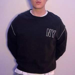 En svart sweatshirt med vita detaljer. Storlek M (jag är 183cm)