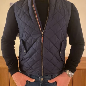 Tommy hilfiger väst - Denna begagnade stilrena Tommy Hilfiger västen är ett perfekt plagg att lägga till i din gaderob för en billig peng. Den är gjord av högkvalitativa material och har den ikoniska Tommy Hilfiger logan på bröstet. Den har inga som helst defekter! Cond 9/10👔⚡️