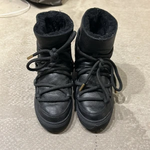 Inuikii  - Inuikii svarta helt i skinn med fårskinn och rosedetalj. Uppbyggda inuti