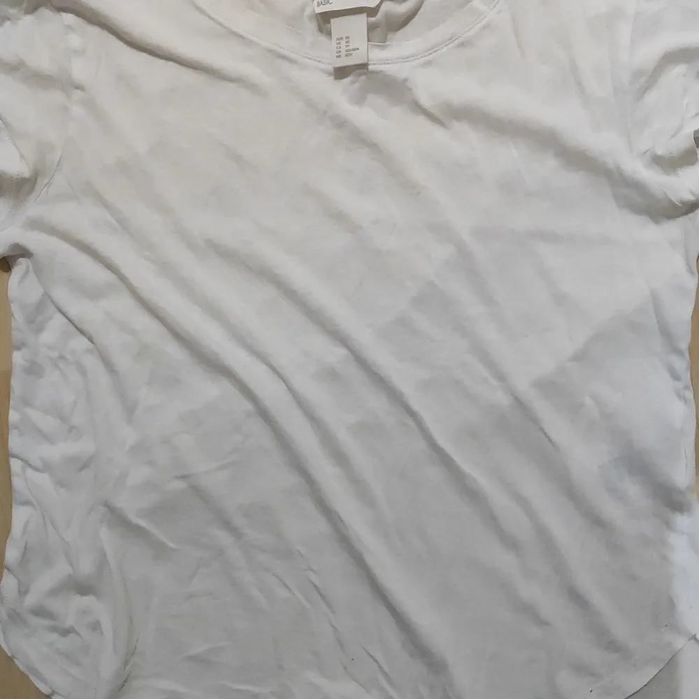 En enkel helt vit T-shirt. Rundad i neder kanten. T-shirts.