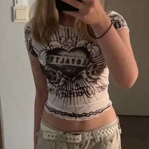 Ed hardy liknande tröja - Vit t-shirt med svart ed hardy liknande tryck i storlek M. Den passar S också och är stretchig. Säljer pågrund av att den inte kommer till användning då den inte är min stil längre. Använd fåtal gånger, inga hål eller fläckar. Köparen står för frakten!