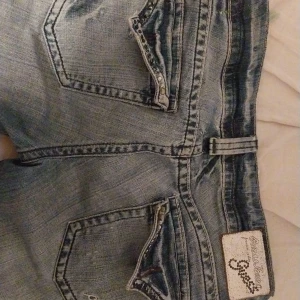 Low waisted guess jeans - Jätte fina guess jeans, knapparna på fickorna är sönder. Säljer dessa byxor för det är för stora.