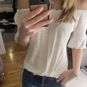 Vit blus/t-shirt - Jätte fin off shoulder t-shirt med volanger på ärmarna. Lätt att matcha och till vardag eller finare tillfällen. Nyckick💘