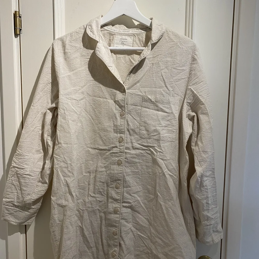 Mysig och skön nattskjorta från Primark, stl. 38, som räcker ovanför knäna. Begie-vit randig. Knappt använd. Ärmarna går att vika upp och fästa med en knapp.  . Skjortor.