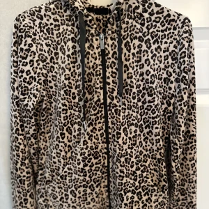 Hoodie/kofta i sammet/plysch - Helt oanvänd hoodie/kofta i sammet/plysch från Gina Tricot, stl XS. Leopardmönstrad med svarta sidenband framtill. Luva & fickor. 