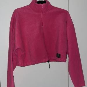 Croppad fleecetröja med dragsko - Ceriserosa croppad fleecetröja med halvzip och hög krage från Urban Outfitters