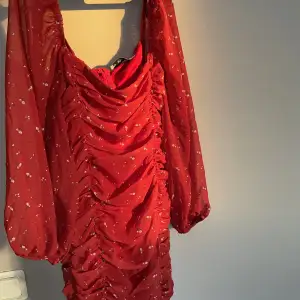 Röd klänning med blommönster. Dragkedja på ryggen. Tight och lagom kort med mesh material. 