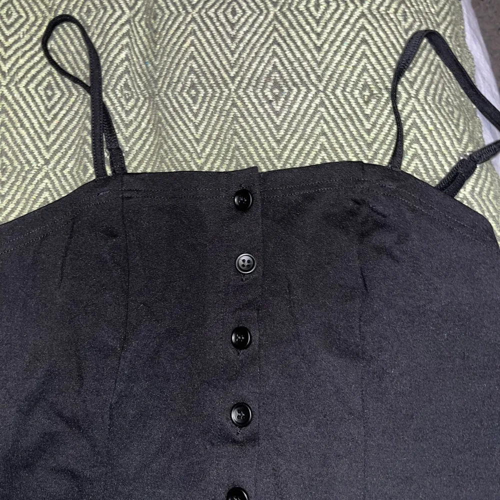 Ett figurnära svart linne med knappning🖤🖤. Skulle säga att materialet påminner lite om ”Sharpeware”- kläder, så sätter sig på kroppen väldigt snyggt och ger även stöd för bysten. . Toppar.