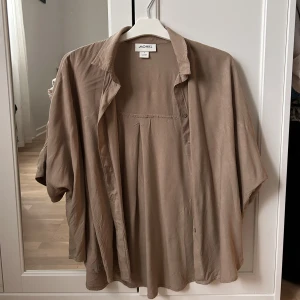 Kortärmad skjorta  - Tunn skjorta från Monki i ljusbrun /khaki. Använt många gånger sen den köptes 2020 (bild 2 från 2022, bild 3 från 2021) stor i storlek! Fortfarande bra skick dock 🥰