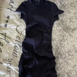 Ribbad klänning med snörning längst med sidorna så man kan göra klänningen till den längden man vill.