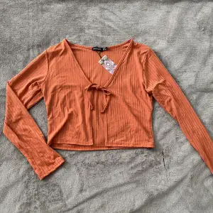 Aldrig använd, har 3 stycken likadan. Orange långärmad tröja med knytning fram, storlek 38🤍 Köpare står för fraktkostnaden!
