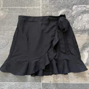 Säljer en svart kjol med volang och snörning. Använd ett fåtal gånger:)
