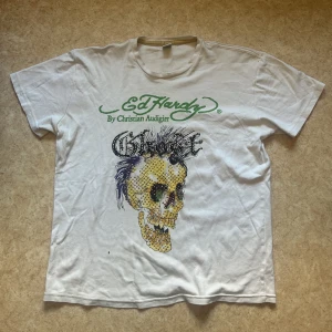 Ed hardy t shirt med rhinestones - Jättefin ed hardy t shirt med rhinestone storlek XXL men sitter mer som en vanlig L ren och fin men några stygn har gått upp i armhålan som man enkelt kan laga eller bara strunta i :)