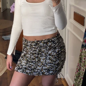 Kjol - Säljer denna somriga kjol med mönster av blommor på. Kjolen har även Knyt detaljer vid benen samt dragkedja bak.  Har använt kjolen ett Antal gånger.