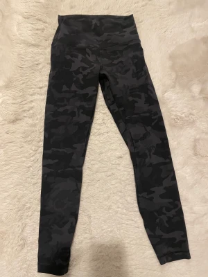 Lululemon Align 25” 4 - Lululemon Align i camo svart/grå färg i storlek 4. Motsvarar S! Väl omhändertagna. Endast tvättade ut och in med tvättmedel samt i 30 grader! Ser nya ut! Nypris ca 1100-1200kr