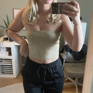 Guld glittrig topp - Guld-glittrig bandeau topp från NA-KD. Bra skick då jag bara har använt den en gång